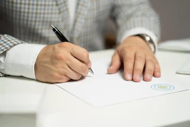 Hand signing a document on a desk