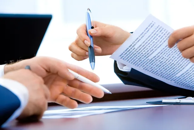Two people reviewing and signing a document at a desk