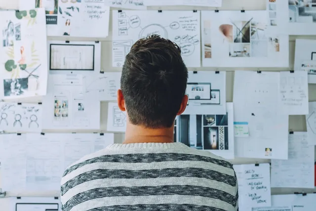 Professional studying a wall full of pinned references and ideas